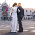 Couple In White Dress And Black Suit Walking In Venice Square With Historic Architecture
