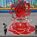 Giant Red Rose Sculpture Illuminated At Night With City Skyline And People Around