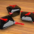 Three Black Cookware Pieces With Red Handles And Lids On Wooden Table