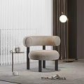 Beige Accent Chair With Round Armrests And Black Legs By Floor Lamp And Side Table