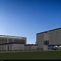 Industrial Factory With Blue Roofs Surrounded By Green Trees And Access Road With Trucks