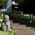 Stone Stepping Path in Garden with Green Lawn Trees Stone Lanterns and Monk Statues