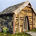 Rustic Outdoor Cottage With Stone Wood Walls Tile Roof Arched Door Grass And Yellow Flowers
