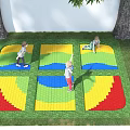 Outdoor Children's Play Area With Colorful Geometric Mats And Kids Playing On Grass
