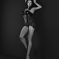 Woman in Black Corset with Lace Details Posing Against Dark Background