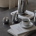 Elegant Stainless Steel Tea Set With White Cup Saucer And Magazines On Gray Table