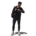 A man with backpack wearing black jacket and pants checking watch in white shoes