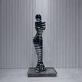 Layered Sculpture Carving Metallic Human Figure With Blue Head Square Base Vertical Striped Gray Wall