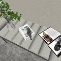 Beige Quilted Footstool with Green Plant Glass Vase and Open Magazines in Living Room