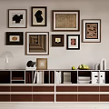 Modern Minimalist Decorative Cabinet Featuring Framed Artworks Above And Table Lamp Books Fruits On Top