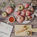 Fresh Vegetables Including Tomatoes and Carrots on Wooden Table with Plate and Cutting Board