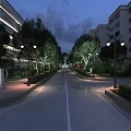 Commercial Street Night View With Lush Green Plants Surrounding Modern Buildings And Warm Lighting