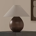 Teardrop Shaped Wooden Table Lamp with Beige Linen Shade on Black Stand and Wall Art