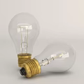 Two Transparent Incandescent Light Bulbs With Golden Bases Standing And Leaning