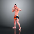 Shirtless Man Practicing Boxing Stance In Orange And Blue Shorts Against Gray Background