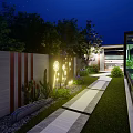 Evening Garden Landscape With Stone Pathway Illuminated Lighting And Green Plants Along Decorative Wall