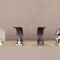 Multiple Modern Faucets In Various Colors And Designs On Light Countertop With Gray Wall