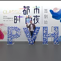 Person Standing By PVH Letters With White Brick Wall And Street Lamps Near Zebra Crossing
