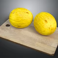 Two fresh yellow melons placed on a natural wooden cutting board