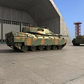 Camouflage Military Tank Parked In Large Warehouse With Red Tower Structure