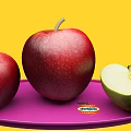 Red Apples and Cut Green Apple on Purple Plate with Yellow Background and Del Monte Label