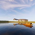 Modern Building In Golden Wheat Field With Sloped Roof And Glass Windows Under Sunset Sky