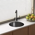 Black Round Kitchen Sink With High Arc Faucet On White Countertop And Glass Fruit Bowl