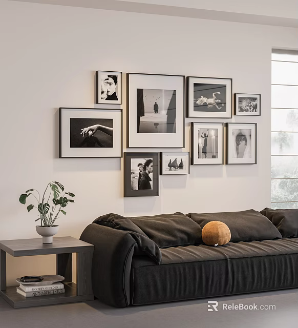 Stylish Photo Wall with Framed Black and White Pictures Above Dark Sofa and Green Plant 3d model 