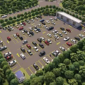 Aerial View of Parking Lot with Many Cars Surrounded by Green Trees and Building