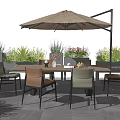 Outdoor Table And Chair Set With Umbrella Surrounded By Plants And Flowers On Gray Flooring