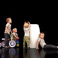 Group of children playing around white pillar with tricycle and various poses
