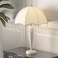 White Decorative Table Lamp With Umbrella Shaped Lampshade Beaded Fringes And Cylindrical Base With Gold Trim