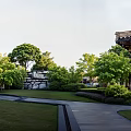 Traditional Courtyard Garden With Lush Trees Shrubs Stone Pathway Green Lawn And Stone Wall