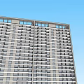 Modern High Rise Office Building With Glass Facade And Multiple Windows Against Clear Blue Sky
