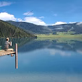 Serene Lake Landscape With Wooden Dock Person Fishing Calm Water Mountain Reflections Blue Sky Forest