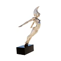 Golden Female Figure Sculpture On Black Base Against Blue Sky Sandy Landscape