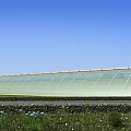 Modern Industrial Factory Building With Arched Glass Roof Under Blue Sky And Green Grass