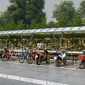 Outdoor Charging Station With Canopy For Parked Motorcycles And Bicycles Near Trees