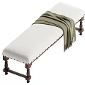 White Padded Bench With Brown Wooden Legs And Green Draped Blanket