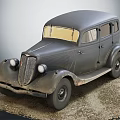 Vintage Black Car with Retro Grille Headlights and Old Tires on Gravel Ground