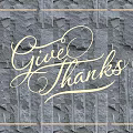 Illuminated Lighting Combination Featuring Handwritten Give Thanks Text and Glowing Frame on Black Stone Wall