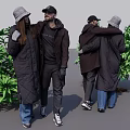 Two People Interacting And Hugging In Coats With Hats Near Green Plants And Blue Sky