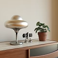 Modern Metallic Silver Table Lamp With Green Plant Small Clock And Wooden Table
