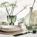 White Ceramic Dinnerware Set With Plates Bowls Green Glass Vases And Decorative Branches On Tabletop