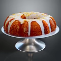 Delicious Round Bundt Cake With White Icing Drizzle On Silver Stand Against Dark Background