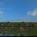 Scenic Park Landscape With Lake Willow Trees Flowering Plants And Traditional Buildings Under Blue Sky