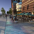 Vibrant Commercial Street with Paved Walkway Red Brick Buildings Green Umbrellas and Outdoor Dining Areas