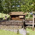 Rustic Lodge With Thatched Roof Wooden Platform And Outdoor Rest Area Surrounded By Green Trees