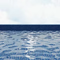 Serene Swimming Pool With Blue Tile Edge And Calm Water Surface Under Cloudy Sky View