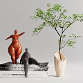 Decorative Figurine Set with Orange Standing Gray Reclining Sculptures on Books and White Vase Greenery